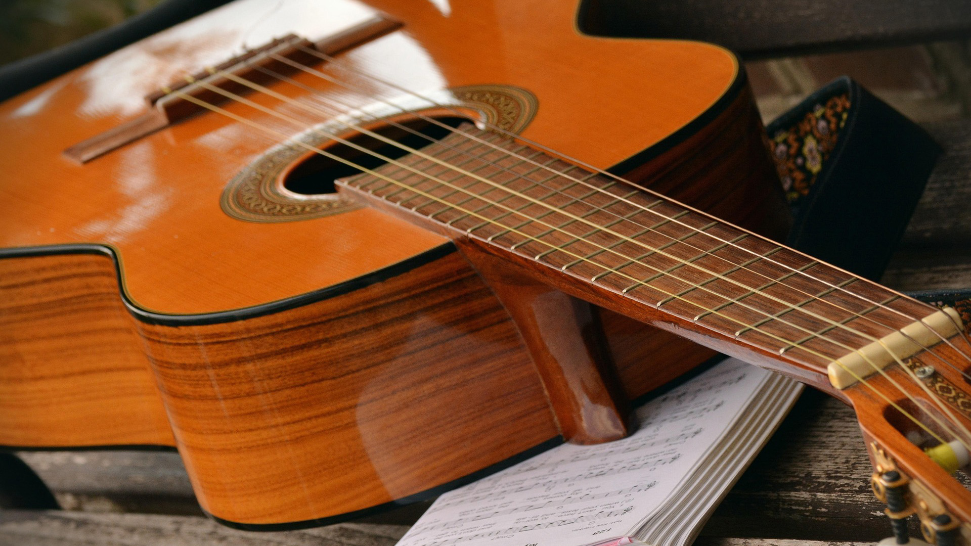 Acoustic guitar resting on an open songbook with chord sheets